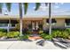 Inviting home exterior with a red brick facade, double doors, and lush landscaping creating a welcoming entrance at 650 Poinsettia Rd, Belleair, FL 33756