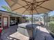 Covered patio with a hot tub, seating, and an umbrella, ideal for relaxation at 650 Poinsettia Rd, Belleair, FL 33756