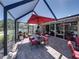 Inviting screened patio featuring a dining set with an umbrella and a view of the lush garden at 650 Poinsettia Rd, Belleair, FL 33756