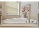 Corner bathtub with neutral tile surround and a floral painting creates a spa-like retreat at 2709 Coco Palm Cir, Wesley Chapel, FL 33543