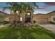 Elegant two-story home featuring a three-car garage, manicured lawn, and vibrant tropical landscaping at 2709 Coco Palm Cir, Wesley Chapel, FL 33543