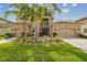 Elegant two-story home featuring a three-car garage, manicured lawn, and vibrant tropical landscaping at 2709 Coco Palm Cir, Wesley Chapel, FL 33543