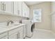 Clean laundry room with white cabinetry, sink, and modern washer and dryer at 2709 Coco Palm Cir, Wesley Chapel, FL 33543