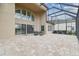 This covered patio features stone floors and an outdoor dining table with wrought-iron chairs at 2709 Coco Palm Cir, Wesley Chapel, FL 33543