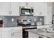 Bright kitchen featuring white cabinets, stainless steel appliances, and a gray backsplash at 7617 Wallflower Trl, Wesley Chapel, FL 33545