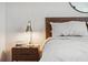 This bedroom includes a wooden bedside table with a modern lamp and books for leisure at 7617 Wallflower Trl, Wesley Chapel, FL 33545