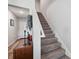 Carpeted staircase with wooden banister and accent table with decor near the front door at 7617 Wallflower Trl, Wesley Chapel, FL 33545