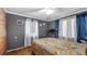 A cozy bedroom with gray walls, light-colored curtains, and a colorful bedspread at 18218 Railroad Rd, Spring Hill, FL 34610