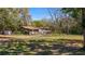 Exterior view of home with brown siding, manicured lawn and mature trees at 18218 Railroad Rd, Spring Hill, FL 34610