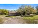 Exterior view of house, large trees, a storage building and a dirt driveway at 18218 Railroad Rd, Spring Hill, FL 34610