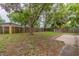 Large backyard with a wooden fence, mature trees, and a paved patio area at 4129 Highland Loop, New Port Richey, FL 34652