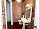 Unique powder room showcasing brick walls, pedestal sink, and modern fixtures at 1570 Oakford Rd, Sarasota, FL 34240