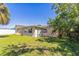A sunny backyard featuring a grass lawn and the exterior of a single-story home with white-trimmed windows at 10105 Vineyard Ln, Port Richey, FL 34668