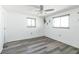 Bright bedroom with modern gray flooring, a ceiling fan, and two sunny windows at 10105 Vineyard Ln, Port Richey, FL 34668