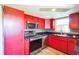Compact kitchen with bright-red cabinets, stainless steel appliances, and a window offering natural light at 10105 Vineyard Ln, Port Richey, FL 34668