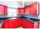 The kitchen features red cabinets, black counter tops, and a window providing natural light at 10105 Vineyard Ln, Port Richey, FL 34668