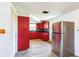 Functional kitchen with stainless steel refrigerator, red cabinets, and wood-look tile at 10105 Vineyard Ln, Port Richey, FL 34668