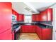 Compact kitchen featuring bright-red cabinets, black countertops, and modern appliances at 10105 Vineyard Ln, Port Richey, FL 34668