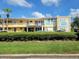 Inviting yellow condo building featuring a well-maintained lawn and mature palm trees at 2155 Wood St # B4, Sarasota, FL 34237
