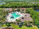 Aerial view of community pool, water slide, splash pad and clubhouse in lush landscaping with palm trees at 13136 Peregrin Cir, Bradenton, FL 34212