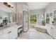 Bright and spacious bathroom featuring dual vanities, a glass-enclosed shower, and a large soaking tub by the window at 13136 Peregrin Cir, Bradenton, FL 34212