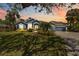 Charming blue home with manicured lawn, lush landscaping and a brick driveway at sunset at 13136 Peregrin Cir, Bradenton, FL 34212