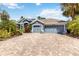 Beautiful blue home featuring a paver driveway, three car garage, and lush landscaping at 13136 Peregrin Cir, Bradenton, FL 34212