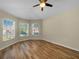Bright bedroom featuring hardwood flooring, neutral walls, and three windows that allow in natural light at 15452 Long Cypress Dr, Ruskin, FL 33573