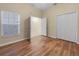 Bright bedroom featuring wood flooring, a double door closet, and a window for natural light at 15452 Long Cypress Dr, Ruskin, FL 33573