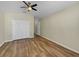 Bedroom features wood flooring, neutral walls, a ceiling fan, and a double-door closet at 15452 Long Cypress Dr, Ruskin, FL 33573