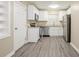 Well-lit kitchen with white cabinets, stainless steel appliances, and sleek gray wood-look flooring at 3645 6Th S St, St Petersburg, FL 33705