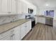 Bright kitchen features white cabinets, stainless steel appliances, granite countertops, and a stylish subway tile backsplash at 8080 Spanish Oak Dr, Spring Hill, FL 34606