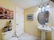 Clean half bath with a pedestal sink, tiled floors, and decorative wall art at 11805 Castine St, New Port Richey, FL 34654