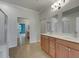 Large bathroom with double vanity, mirrors, and a doorway revealing a bedroom with blue walls and mirrored closet doors at 1181 Burgos Dr # 406, Sarasota, FL 34238
