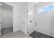 Modern bathroom with tiled shower with window and black pebble floor, next to doorway to closet at 7443 S Seagrape Rd, Punta Gorda, FL 33955