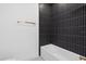 Modern bathroom with white bathtub, black vertical tile backsplash, and gold fixtures at 7443 S Seagrape Rd, Punta Gorda, FL 33955