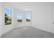 Bright bedroom featuring gray carpet, white walls, baseboards, trim, and large sunny windows at 7443 S Seagrape Rd, Punta Gorda, FL 33955