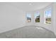 Bright bedroom featuring gray carpet, white walls, baseboards, trim, and large sunny windows at 7443 S Seagrape Rd, Punta Gorda, FL 33955