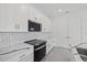 Modern kitchen with white cabinetry, stainless appliances, marble countertops, and stylish subway tile backsplash at 7443 S Seagrape Rd, Punta Gorda, FL 33955
