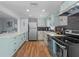 Modern kitchen featuring mint colored cabinets, stainless steel appliances, and black hexagon backsplash at 1805 Rita St, Sarasota, FL 34231