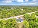 Stunning aerial view of a modern home surrounded by lush greenery and a beautiful blue sky at 18399 Hillsborough Blvd, Port Charlotte, FL 33954