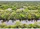 Aerial view of a house located next to a beautiful, reflective canal surrounded by lush green trees at 18399 Hillsborough Blvd, Port Charlotte, FL 33954