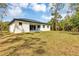 Back exterior view of modern home featuring a large, grassy yard and slider doors to covered patio at 18399 Hillsborough Blvd, Port Charlotte, FL 33954