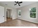 Comfortable bedroom with wood-look flooring, a ceiling fan, and views of mature trees at 18399 Hillsborough Blvd, Port Charlotte, FL 33954