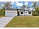 Beautiful white single-story home with a gray driveway and well-manicured lawn under a bright blue sky at 18399 Hillsborough Blvd, Port Charlotte, FL 33954