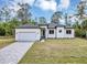 Front exterior view showcasing the contemporary design, manicured lawn, and paved driveway at 18399 Hillsborough Blvd, Port Charlotte, FL 33954