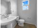 Bright bathroom featuring a pedestal sink, toilet, and window with blue skies at 8869 White Sage Loop, Lakewood Ranch, FL 34202