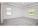 Bright bedroom featuring a tray ceiling, neutral carpet, and two large windows at 25372 Alicante Dr, Punta Gorda, FL 33955