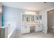 Bright bathroom featuring dual sinks with a large vanity and a bathtub at 31028 Baclan Dr, Wesley Chapel, FL 33545