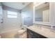 A white bathroom with marble countertop and a tub with shower at 31028 Baclan Dr, Wesley Chapel, FL 33545